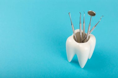 Mavi arkaplandaki dişçi aletleri. Diş hekimi konsepti. Diş bakımı, diş sağlığı konsepti. Ağız boşluğuna dikkat etmek anlamına geliyor. Diş modeli ve dişçi aletleri. Diş hijyeni. Mesaj için yer var. Boşluğu kopyala.