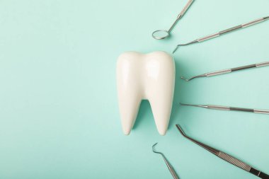Mavi arkaplandaki dişçi aletleri. Diş hekimi konsepti. Diş bakımı, diş sağlığı konsepti. Ağız boşluğuna dikkat etmek anlamına geliyor. Diş modeli ve dişçi aletleri. Diş hijyeni. Mesaj için yer var. Boşluğu kopyala.