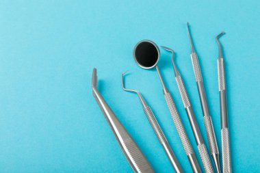 Mavi arkaplandaki dişçi aletleri. Diş hekimi konsepti. Diş bakımı, diş sağlığı konsepti. Ağız boşluğuna dikkat etmek anlamına geliyor. Diş modeli ve dişçi aletleri. Diş hijyeni. Mesaj için yer var. Boşluğu kopyala.