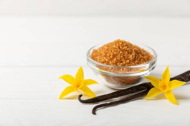 Aromatik vanilya şekeri. Vanilya kabukları. Vanilya çubukları, esmer ve beyaz şeker dokulu arka planda bir kasede. Vanilya çiçekleri, baharatlar ve tatlı ve pişirme için bitkiler. Mesaj için yer var. Boşluğu kopyala