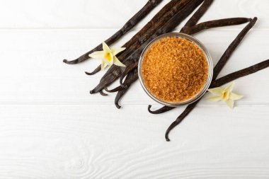 Aromatik vanilya şekeri. Vanilya kabukları. Vanilya çubukları, esmer ve beyaz şeker dokulu arka planda bir kasede. Vanilya çiçekleri, baharatlar ve tatlı ve pişirme için bitkiler. Mesaj için yer var. Boşluğu kopyala