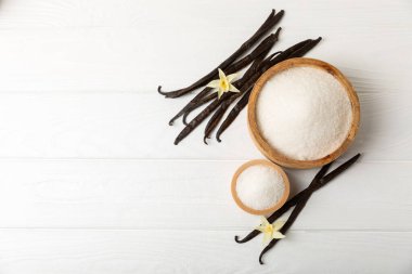 Aromatik vanilya şekeri. Vanilya kabukları. Vanilya çubukları, esmer ve beyaz şeker dokulu arka planda bir kasede. Vanilya çiçekleri, baharatlar ve tatlı ve pişirme için bitkiler. Mesaj için yer var. Boşluğu kopyala