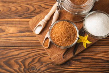 Aromatik vanilya şekeri. Vanilya kabukları. Vanilya çubukları, esmer ve beyaz şeker dokulu arka planda bir kasede. Vanilya çiçekleri, baharatlar ve tatlı ve pişirme için bitkiler. Mesaj için yer var. Boşluğu kopyala