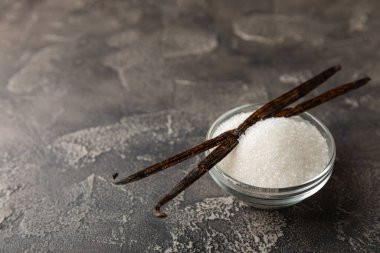 Aromatik vanilya şekeri. Vanilya kabukları. Vanilya çubukları, esmer ve beyaz şeker dokulu arka planda bir kasede. Vanilya çiçekleri, baharatlar ve tatlı ve pişirme için bitkiler. Mesaj için yer var. Boşluğu kopyala