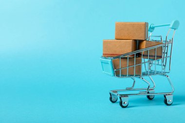 Çevrimiçi alışveriş kavramı. Karton kutu ve parlak renkli bir arka planda tramvayda alışveriş poşetleri. Alışveriş sepeti. İnternetten bilgisayar, tablet, telefon ve kredi kartı kullanarak alışveriş. Eve teslim.