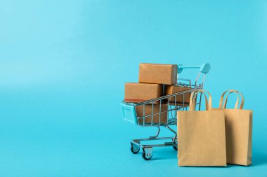 Çevrimiçi alışveriş kavramı. Karton kutu ve parlak renkli bir arka planda tramvayda alışveriş poşetleri. Alışveriş sepeti. İnternetten bilgisayar, tablet, telefon ve kredi kartı kullanarak alışveriş. Eve teslim.