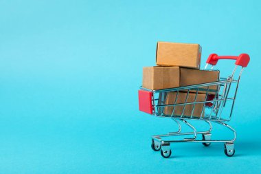 Çevrimiçi alışveriş kavramı. Karton kutu ve parlak renkli bir arka planda tramvayda alışveriş poşetleri. Alışveriş sepeti. İnternetten bilgisayar, tablet, telefon ve kredi kartı kullanarak alışveriş. Eve teslim.