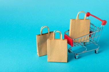 Çevrimiçi alışveriş kavramı. Karton kutu ve parlak renkli bir arka planda tramvayda alışveriş poşetleri. Alışveriş sepeti. İnternetten bilgisayar, tablet, telefon ve kredi kartı kullanarak alışveriş. Eve teslim.