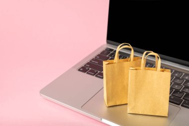 Çevrimiçi alışveriş kavramı. Karton kutu ve parlak renkli bir arka planda tramvayda alışveriş poşetleri. Alışveriş sepeti. İnternetten bilgisayar, tablet, telefon ve kredi kartı kullanarak alışveriş. Eve teslim.