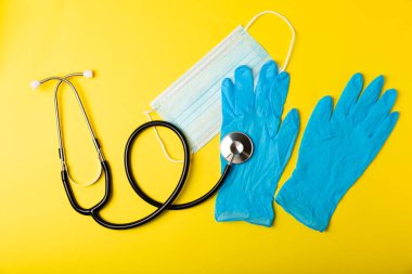 Tıbbi nitril eldivenler, mavi başlık, desenli arka planda tek kullanımlık tıbbi maske. Tıbbi koruyucu giysi. Cerrahi lateks eldivenler. Lastik eldiven üretimi. Tıp konsepti. Üst Manzara. Metni kopyala