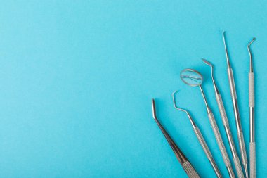 Mavi arkaplandaki dişçi aletleri. Diş hekimi konsepti. Diş bakımı, diş sağlığı konsepti. Ağız boşluğuna dikkat etmek anlamına geliyor. Diş modeli ve dişçi aletleri. Diş hijyeni. Mesaj için yer var. Boşluğu kopyala.