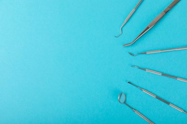 Mavi arkaplandaki dişçi aletleri. Diş hekimi konsepti. Diş bakımı, diş sağlığı konsepti. Ağız boşluğuna dikkat etmek anlamına geliyor. Diş modeli ve dişçi aletleri. Diş hijyeni. Mesaj için yer var. Boşluğu kopyala.