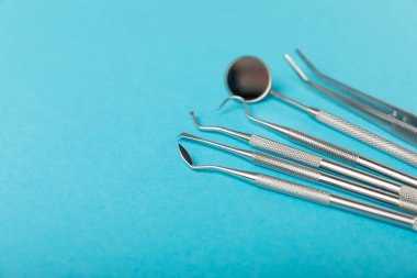 Mavi arkaplandaki dişçi aletleri. Diş hekimi konsepti. Diş bakımı, diş sağlığı konsepti. Ağız boşluğuna dikkat etmek anlamına geliyor. Diş modeli ve dişçi aletleri. Diş hijyeni. Mesaj için yer var. Boşluğu kopyala.