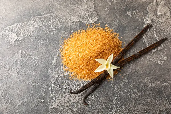 Aromatik vanilya şekeri. Vanilya kabukları. Vanilya çubukları, esmer ve beyaz şeker dokulu arka planda bir kasede. Vanilya çiçekleri, baharatlar ve tatlı ve pişirme için bitkiler. Mesaj için yer var. Boşluğu kopyala