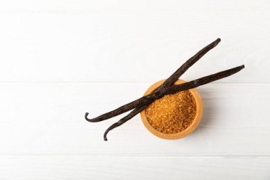 Aromatik vanilya şekeri. Vanilya kabukları. Vanilya çubukları, esmer ve beyaz şeker dokulu arka planda bir kasede. Vanilya çiçekleri, baharatlar ve tatlı ve pişirme için bitkiler. Mesaj için yer var. Boşluğu kopyala