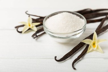Aromatik vanilya şekeri. Vanilya kabukları. Vanilya çubukları, esmer ve beyaz şeker dokulu arka planda bir kasede. Vanilya çiçekleri, baharatlar ve tatlı ve pişirme için bitkiler. Mesaj için yer var. Boşluğu kopyala