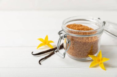 Aromatik vanilya şekeri. Vanilya kabukları. Vanilya çubukları, esmer ve beyaz şeker dokulu arka planda bir kasede. Vanilya çiçekleri, baharatlar ve tatlı ve pişirme için bitkiler. Mesaj için yer var. Boşluğu kopyala