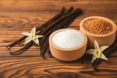 Aromatik vanilya şekeri. Vanilya kabukları. Vanilya çubukları, esmer ve beyaz şeker dokulu arka planda bir kasede. Vanilya çiçekleri, baharatlar ve tatlı ve pişirme için bitkiler. Mesaj için yer var. Boşluğu kopyala