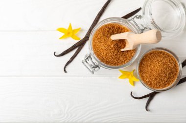 Aromatik vanilya şekeri. Vanilya kabukları. Vanilya çubukları, esmer ve beyaz şeker dokulu arka planda bir kasede. Vanilya çiçekleri, baharatlar ve tatlı ve pişirme için bitkiler. Mesaj için yer var. Boşluğu kopyala