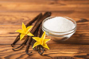 Aromatik vanilya şekeri. Vanilya kabukları. Vanilya çubukları, esmer ve beyaz şeker dokulu arka planda bir kasede. Vanilya çiçekleri, baharatlar ve tatlı ve pişirme için bitkiler. Mesaj için yer var. Boşluğu kopyala