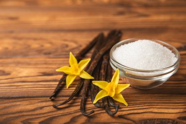 Aromatik vanilya şekeri. Vanilya kabukları. Vanilya çubukları, esmer ve beyaz şeker dokulu arka planda bir kasede. Vanilya çiçekleri, baharatlar ve tatlı ve pişirme için bitkiler. Mesaj için yer var. Boşluğu kopyala