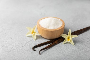 Aromatik vanilya şekeri. Vanilya kabukları. Vanilya çubukları, esmer ve beyaz şeker dokulu arka planda bir kasede. Vanilya çiçekleri, baharatlar ve tatlı ve pişirme için bitkiler. Mesaj için yer var. Boşluğu kopyala