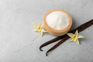 Aromatik vanilya şekeri. Vanilya kabukları. Vanilya çubukları, esmer ve beyaz şeker dokulu arka planda bir kasede. Vanilya çiçekleri, baharatlar ve tatlı ve pişirme için bitkiler. Mesaj için yer var. Boşluğu kopyala