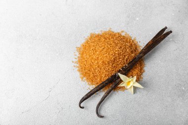 Aromatik vanilya şekeri. Vanilya kabukları. Vanilya çubukları, esmer ve beyaz şeker dokulu arka planda bir kasede. Vanilya çiçekleri, baharatlar ve tatlı ve pişirme için bitkiler. Mesaj için yer var. Boşluğu kopyala