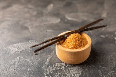 Aromatik vanilya şekeri. Vanilya kabukları. Vanilya çubukları, esmer ve beyaz şeker dokulu arka planda bir kasede. Vanilya çiçekleri, baharatlar ve tatlı ve pişirme için bitkiler. Mesaj için yer var. Boşluğu kopyala