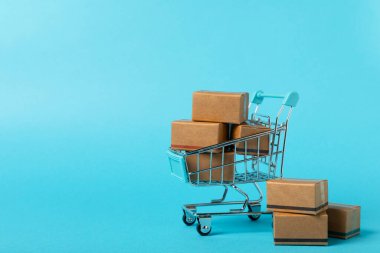 Çevrimiçi alışveriş kavramı. Karton kutu ve parlak renkli bir arka planda tramvayda alışveriş poşetleri. Alışveriş sepeti. İnternetten bilgisayar, tablet, telefon ve kredi kartı kullanarak alışveriş. Eve teslim.