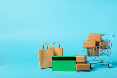 Çevrimiçi alışveriş kavramı. Karton kutu ve parlak renkli bir arka planda tramvayda alışveriş poşetleri. Alışveriş sepeti. İnternetten bilgisayar, tablet, telefon ve kredi kartı kullanarak alışveriş. Eve teslim.