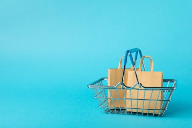 Çevrimiçi alışveriş kavramı. Karton kutu ve parlak renkli bir arka planda tramvayda alışveriş poşetleri. Alışveriş sepeti. İnternetten bilgisayar, tablet, telefon ve kredi kartı kullanarak alışveriş. Eve teslim.