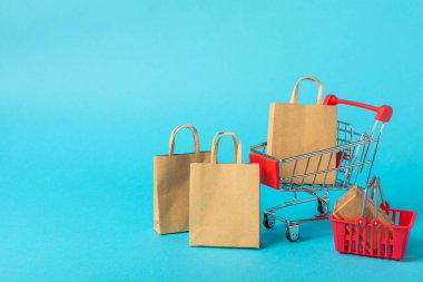 Çevrimiçi alışveriş kavramı. Karton kutu ve parlak renkli bir arka planda tramvayda alışveriş poşetleri. Alışveriş sepeti. İnternetten bilgisayar, tablet, telefon ve kredi kartı kullanarak alışveriş. Eve teslim.