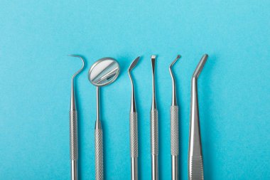 Mavi arkaplandaki dişçi aletleri. Diş hekimi konsepti. Diş bakımı, diş sağlığı konsepti. Ağız boşluğuna dikkat etmek anlamına geliyor. Diş modeli ve dişçi aletleri. Diş hijyeni. Mesaj için yer var. Boşluğu kopyala.
