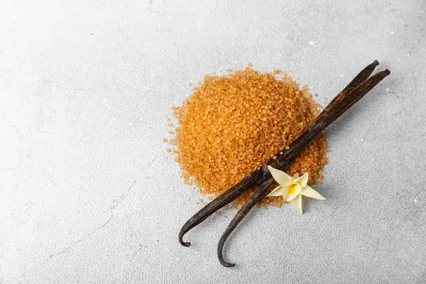 Aromatik vanilya şekeri. Vanilya kabukları. Vanilya çubukları, esmer ve beyaz şeker dokulu arka planda bir kasede. Vanilya çiçekleri, baharatlar ve tatlı ve pişirme için bitkiler. Mesaj için yer var. Boşluğu kopyala