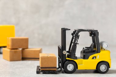 Parlak desenli arka planda sarı forklift. Lojistik konsept. Online alışveriş konsepti için lojistik ve tedarik zinciri yönetimi. Mağazaya mal ya da ürün teslimatı. Karton kutu.