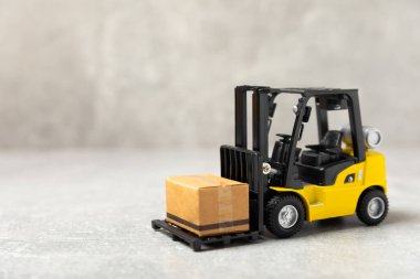 Parlak desenli arka planda sarı forklift. Lojistik konsept. Online alışveriş konsepti için lojistik ve tedarik zinciri yönetimi. Mağazaya mal ya da ürün teslimatı. Karton kutu.