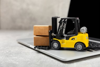 Parlak desenli arka planda sarı forklift. Lojistik konsept. Online alışveriş konsepti için lojistik ve tedarik zinciri yönetimi. Mağazaya mal ya da ürün teslimatı. Karton kutu.