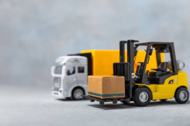 Sarı forklift ve parlak arka planda sarı kamyon. Lojistik konsept. Online alışveriş için lojistik ve tedarik zinciri yönetimi. Mağazaya mal ya da ürün teslimatı. Karton kutu..
