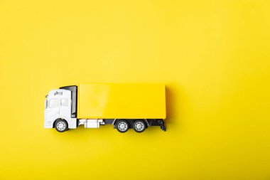 Parlak bir arka planda sarı kamyonlar ve karton kutular. Konsept lojistik, dağıtım ve ulaşım temaları. Dünyanın dört bir yanındaki bir mağazaya mal ya da ürün teslimatı. Karton kutu. Metin için boşluk. 