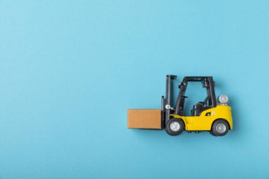 Parlak desenli arka planda sarı forklift. Lojistik konsept. Online alışveriş konsepti için lojistik ve tedarik zinciri yönetimi. Mağazaya mal ya da ürün teslimatı. Karton kutu.