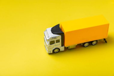 Parlak bir arka planda sarı kamyonlar ve karton kutular. Konsept lojistik, dağıtım ve ulaşım temaları. Dünyanın dört bir yanındaki bir mağazaya mal ya da ürün teslimatı. Karton kutu. Metin için boşluk. 