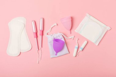 Aybaşı kupası, parlak bir arka plan. Hijyenik peçeteler, tamponlar ve regl kupası. Kritik günler, regl dönemi kavramı. Kadın hijyen ürünü. Kadın sağlığı kavramı. Adet öncesi sendromu. Boşluğu kopyala