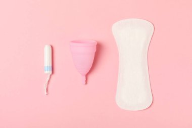 Aybaşı kupası, parlak bir arka plan. Hijyenik peçeteler, tamponlar ve regl kupası. Kritik günler, regl dönemi kavramı. Kadın hijyen ürünü. Kadın sağlığı kavramı. Adet öncesi sendromu. Boşluğu kopyala