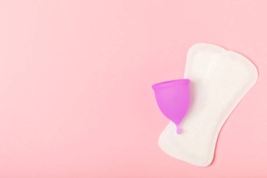 Aybaşı kupası, parlak bir arka plan. Hijyenik peçeteler, tamponlar ve regl kupası. Kritik günler, regl dönemi kavramı. Kadın hijyen ürünü. Kadın sağlığı kavramı. Adet öncesi sendromu. Boşluğu kopyala