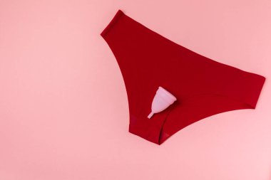 Aybaşı kupası, parlak bir arka plan. Hijyenik peçeteler, tamponlar ve regl kupası. Kritik günler, regl dönemi kavramı. Kadın hijyen ürünü. Kadın sağlığı kavramı. Adet öncesi sendromu. Boşluğu kopyala