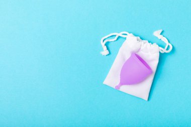 Aybaşı kupası, parlak bir arka plan. Hijyenik peçeteler, tamponlar ve regl kupası. Kritik günler, regl dönemi kavramı. Kadın hijyen ürünü. Kadın sağlığı kavramı. Adet öncesi sendromu. Boşluğu kopyala
