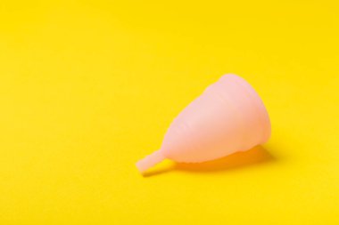 Aybaşı kupası, parlak bir arka plan. Hijyenik peçeteler, tamponlar ve regl kupası. Kritik günler, regl dönemi kavramı. Kadın hijyen ürünü. Kadın sağlığı kavramı. Adet öncesi sendromu. Boşluğu kopyala