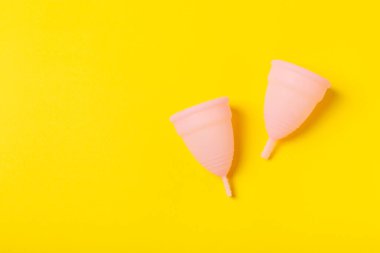 Aybaşı kupası, parlak bir arka plan. Hijyenik peçeteler, tamponlar ve regl kupası. Kritik günler, regl dönemi kavramı. Kadın hijyen ürünü. Kadın sağlığı kavramı. Adet öncesi sendromu. Boşluğu kopyala