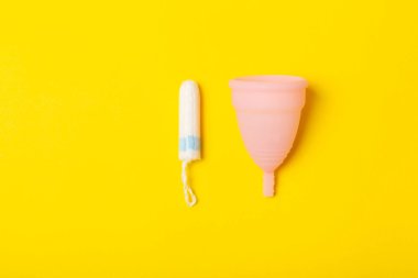 Aybaşı kupası, parlak bir arka plan. Hijyenik peçeteler, tamponlar ve regl kupası. Kritik günler, regl dönemi kavramı. Kadın hijyen ürünü. Kadın sağlığı kavramı. Adet öncesi sendromu. Boşluğu kopyala